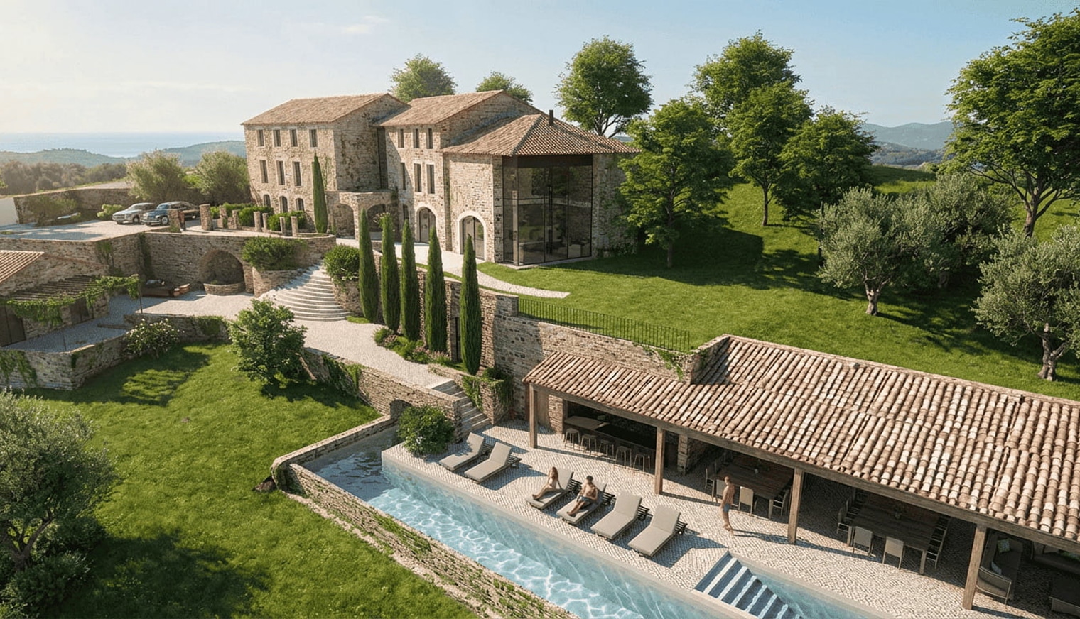 Grande villa en pierre sur plusieurs niveaux, avec piscine où se détendent des personnes. Le domaine est entouré de pelouses, cyprès et oliviers, dominant collines verdoyantes et mer lointaine.