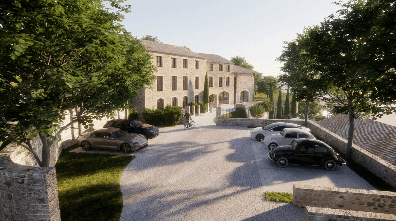 Plusieurs voitures sont garées sur une cour pavée devant un grand bâtiment en pierre. Une personne y roule à vélo, entourée d'arbres sous un ciel clair.